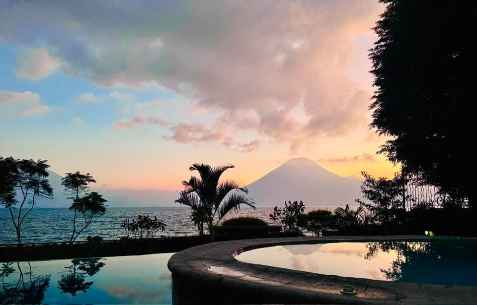 The infinity pool at dusk, palms silhouetted against the volcano beyond